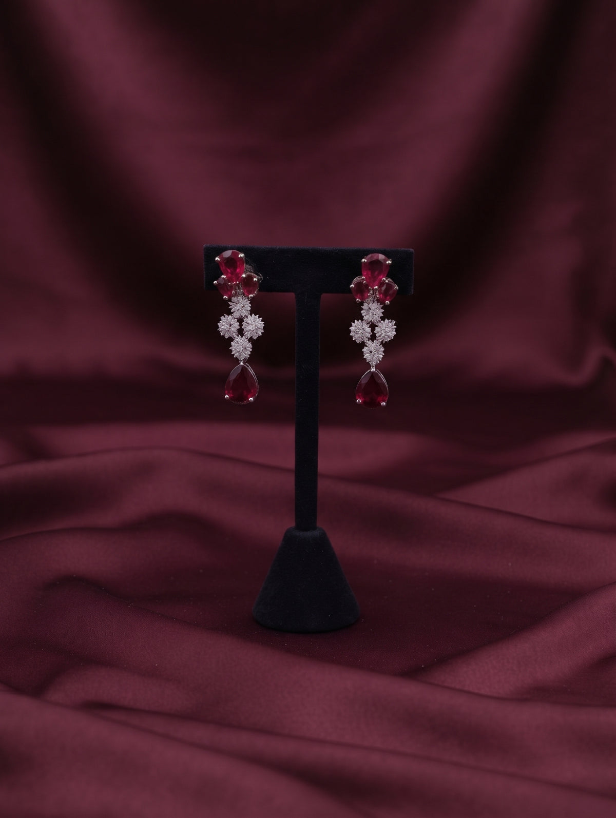 Stylish rhodium plated necklace and earring set adorned with sparkling maroon CZ crystals.
