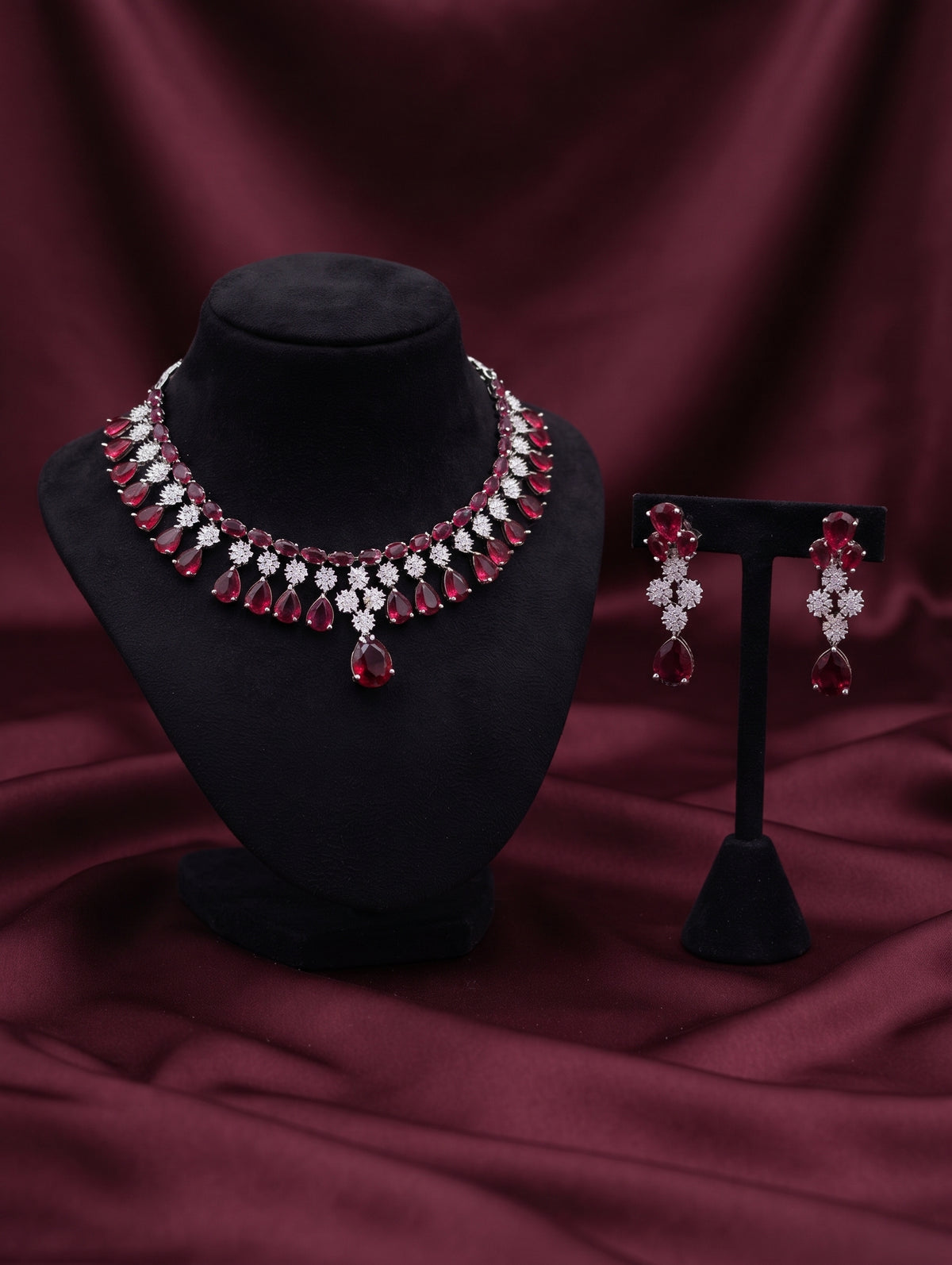 Stylish rhodium plated necklace and earring set adorned with sparkling maroon CZ crystals.